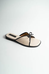 Beige sandal with a black strap on a light gray background