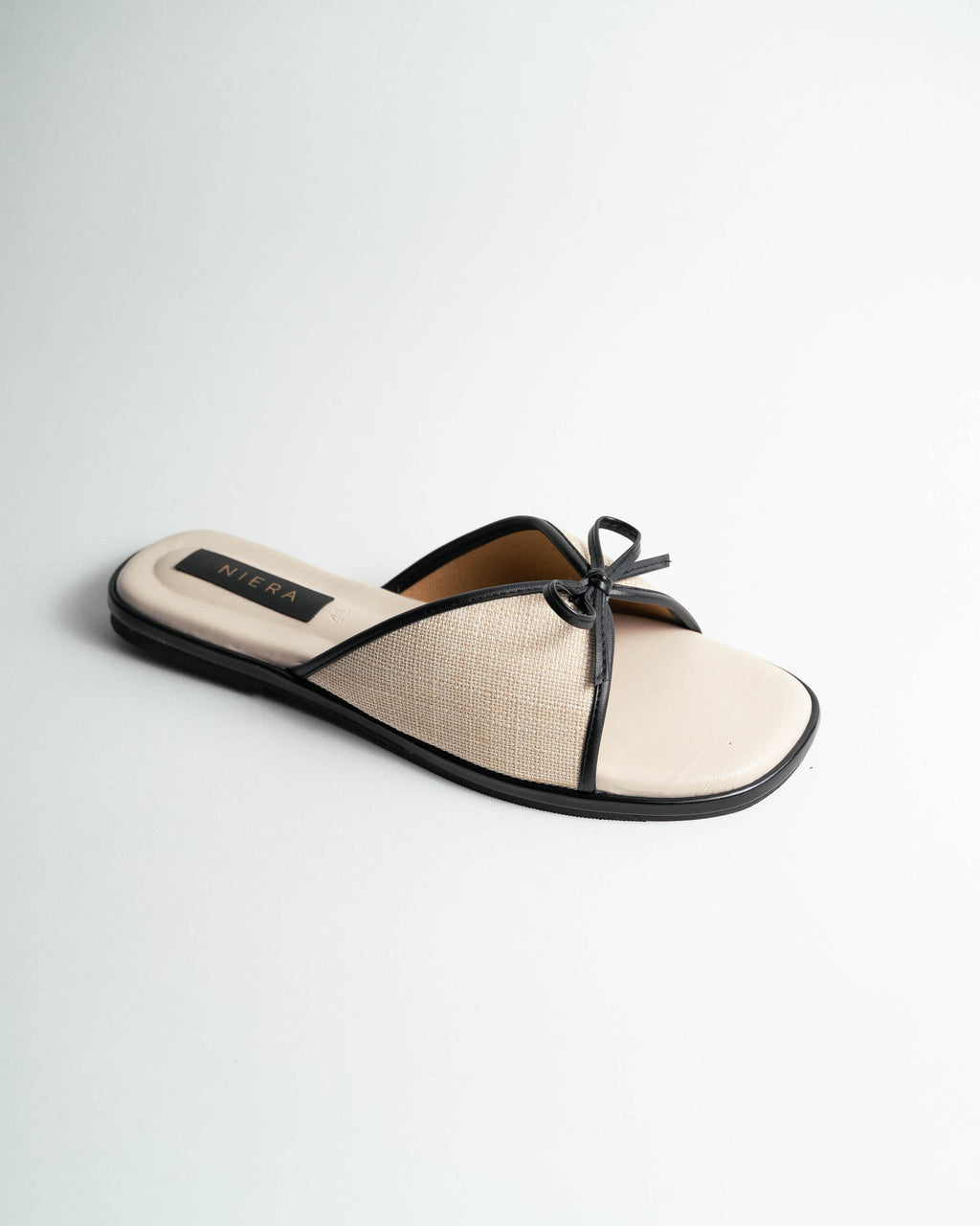 Beige sandal with a black strap on a light gray background