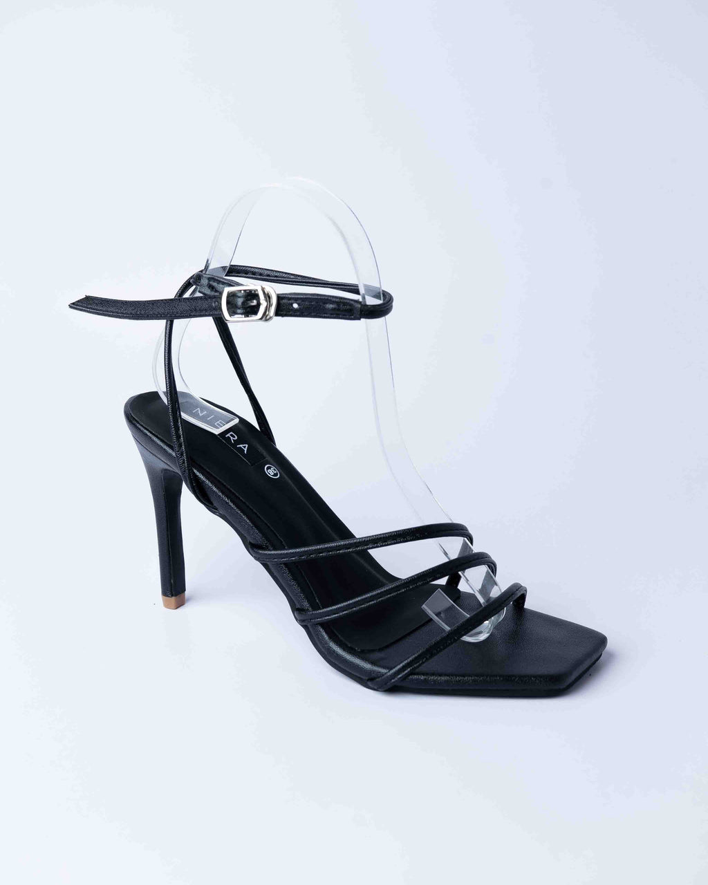 Black high-heeled sandal with thin straps on a light gray background